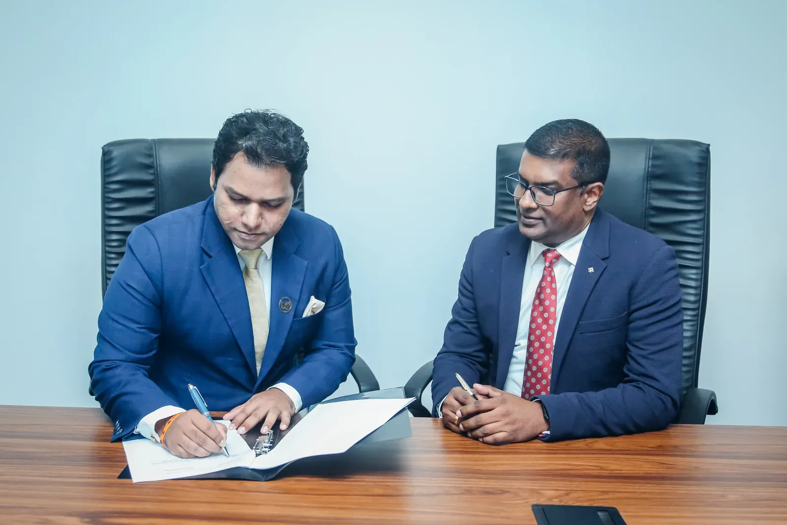 Tanuj Edward of Orient Insurance signing the partnership agreement, seated beside a GPS Group colleague