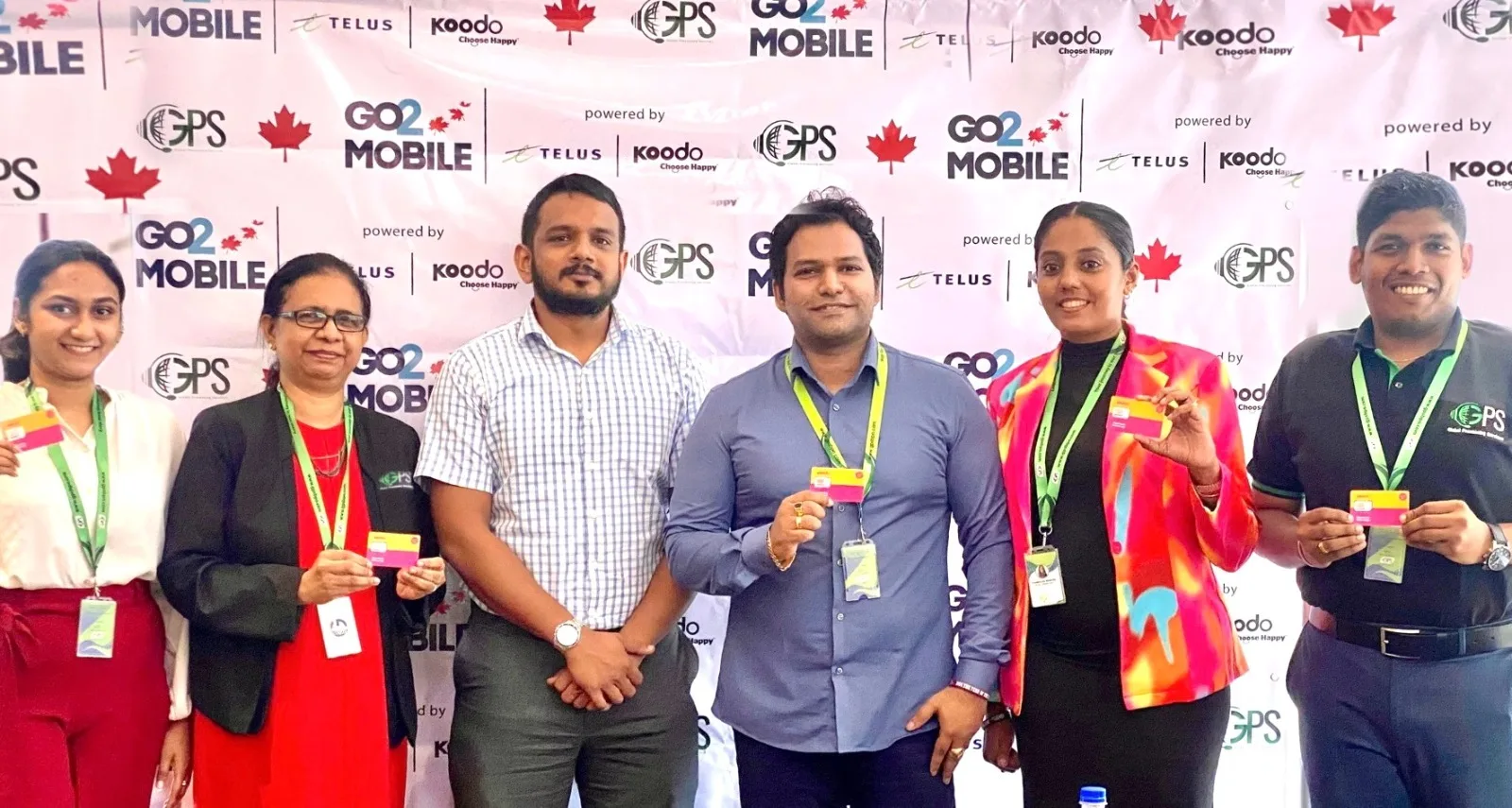Six GPS colleagues holding Go2Canada Mobile SIM cards at the launch, in front of a backdrop carrying the Go 2 Mobile, TELUS, Koodo and GPS marks